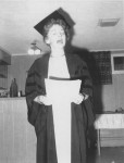 Image of Clara Thomas in graduation gown reading from a text, 1962. Clara Thomas fonds, F0432, image no. ASC00513.